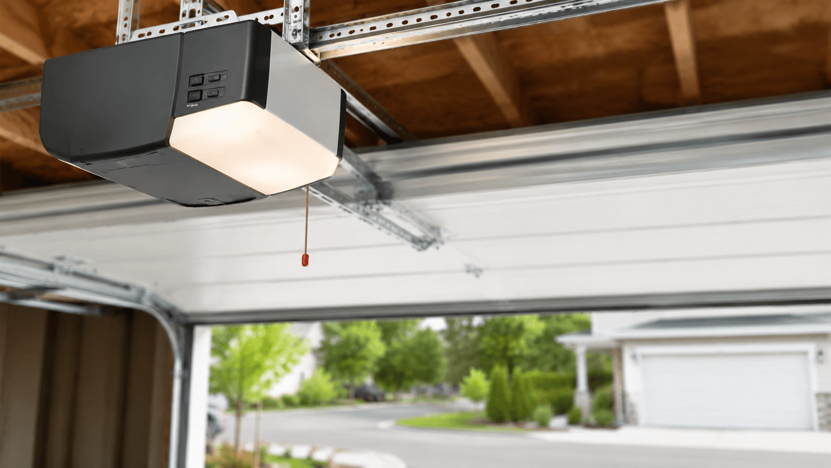 Ceiling-mounted garage door opener with its light on inside a residential garage.