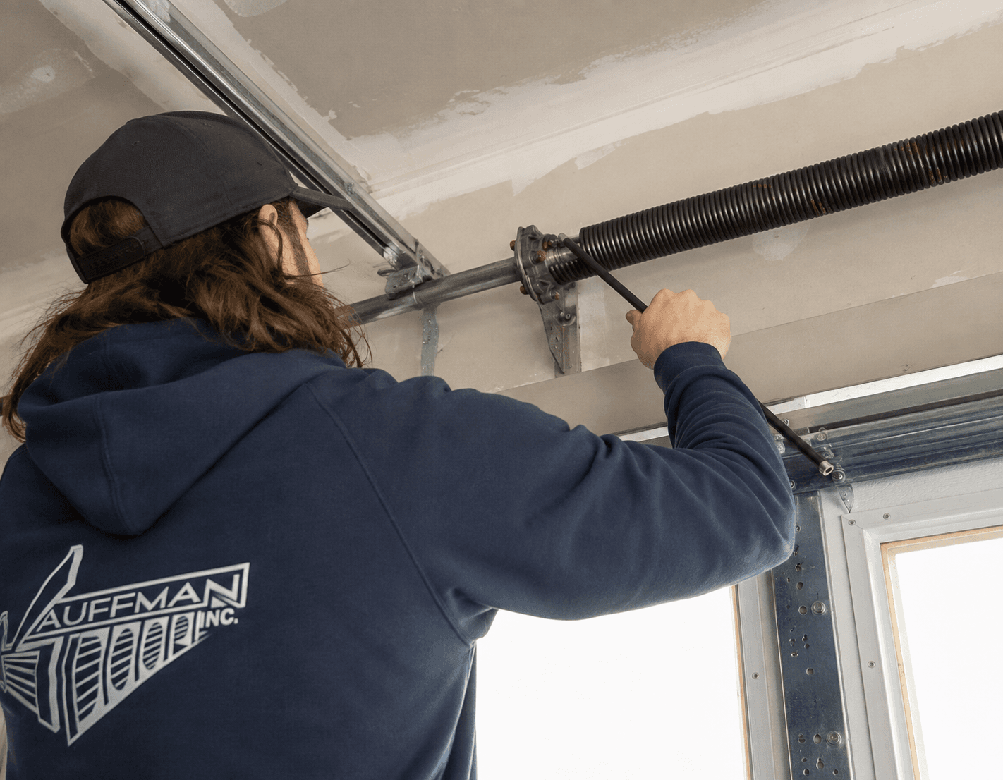 Garage door technician replacing a torsion spring inside a residential garage.